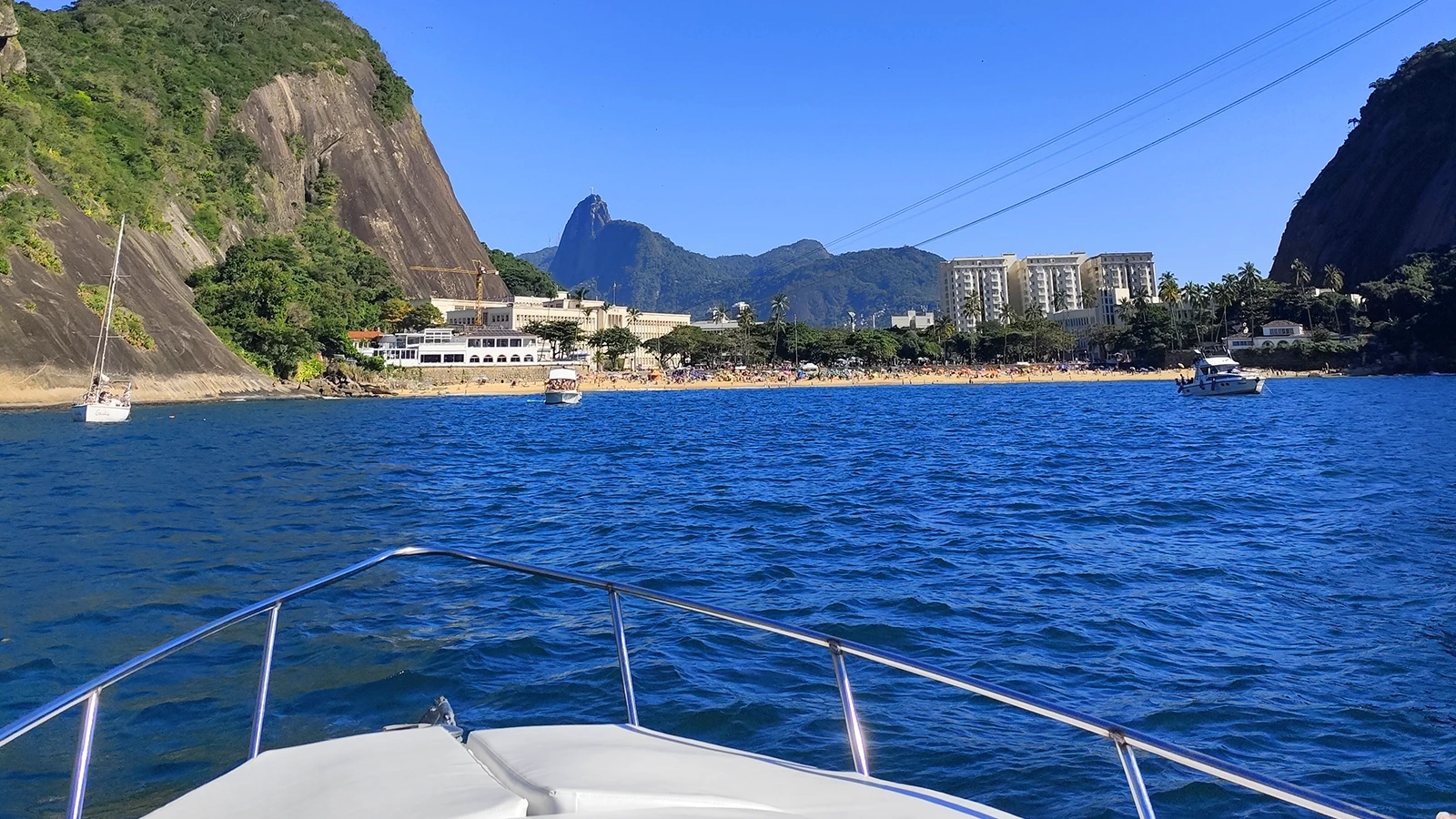 Barco navegando na Baía de Guanabara com o Cristo Redentor e Pão de Açúcar ao fundo