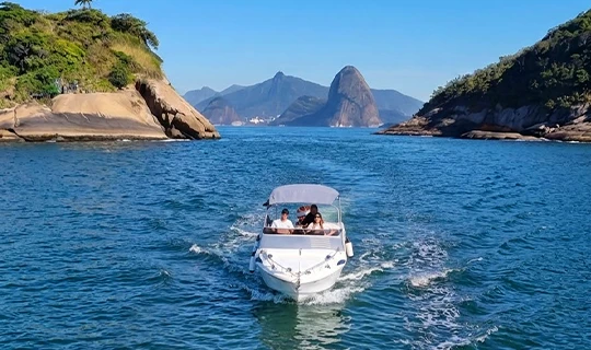 Barco navegando entre ilhas da Baía de Guanabara com o Pão de Açúcar ao fundo